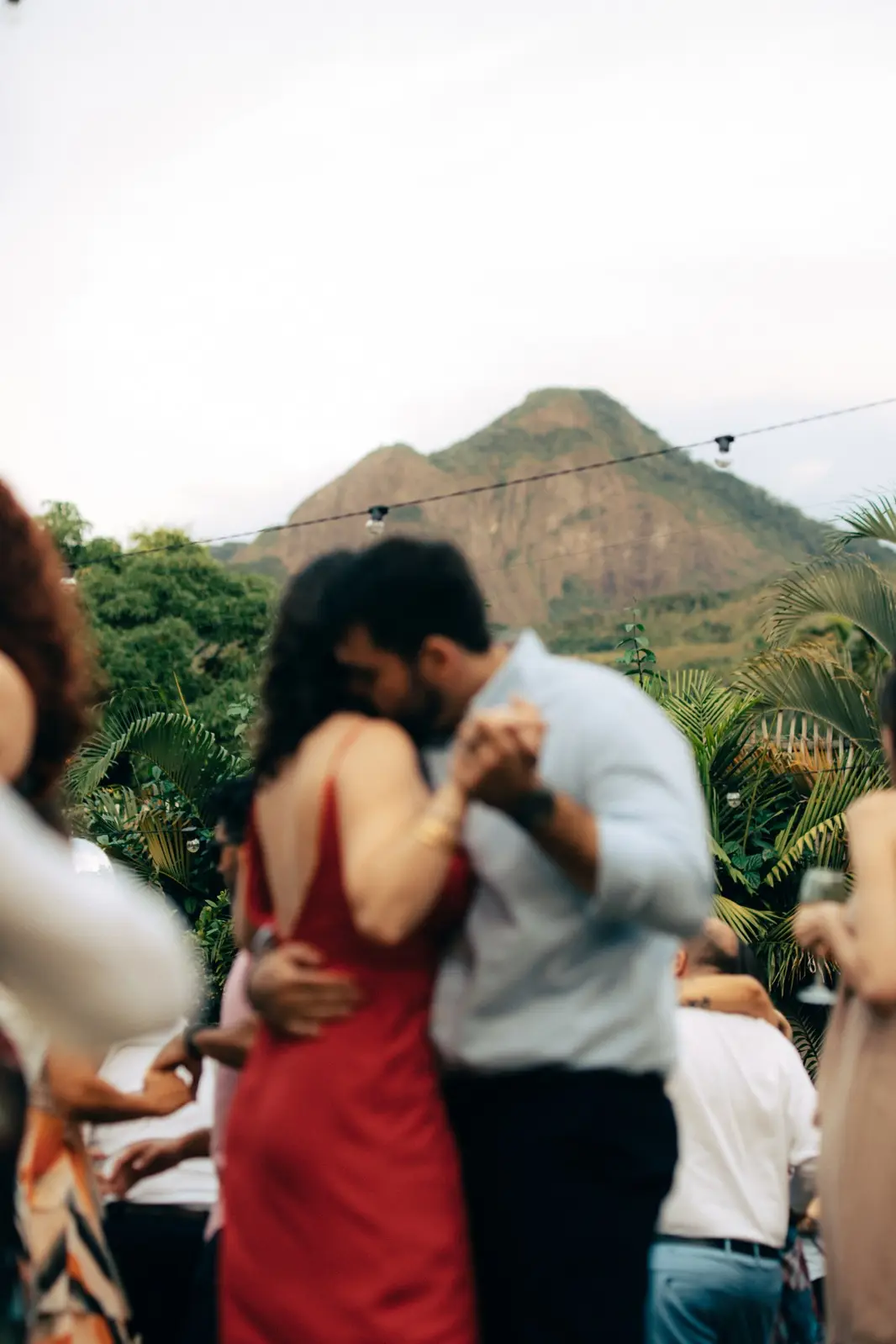 Casal dançando abraçado no meio dos convidados, com a serra e o Pico do Baepi atrás.